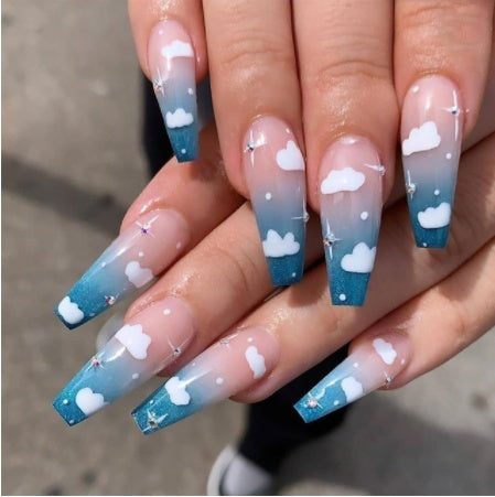 Wearing Nails design featuring blue ombre false nails with white cloud patterns and sparkling accents.