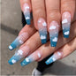 Wearing Nails design featuring blue ombre false nails with white cloud patterns and sparkling accents.